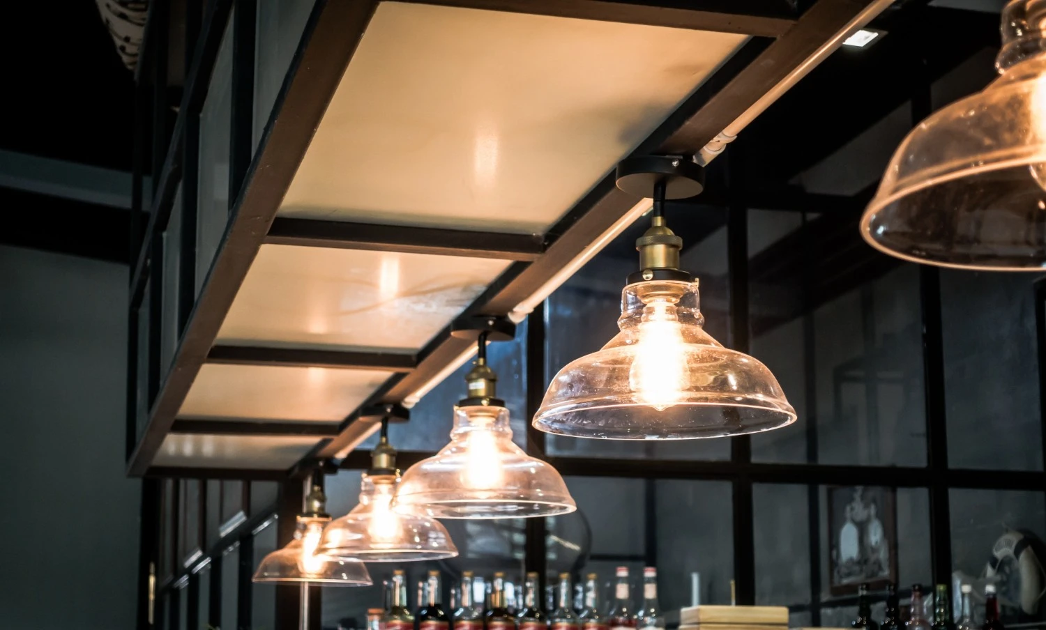 A bar featuring multiple light bulbs suspended from the ceiling creating an inviting atmosphere for