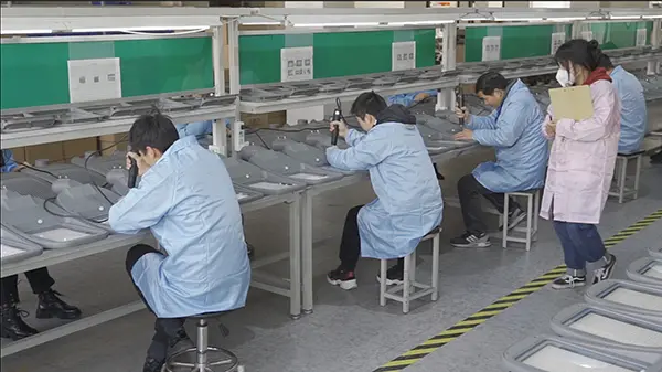 Workers at the AllGreen factory are seen diligently assembling products at a production line