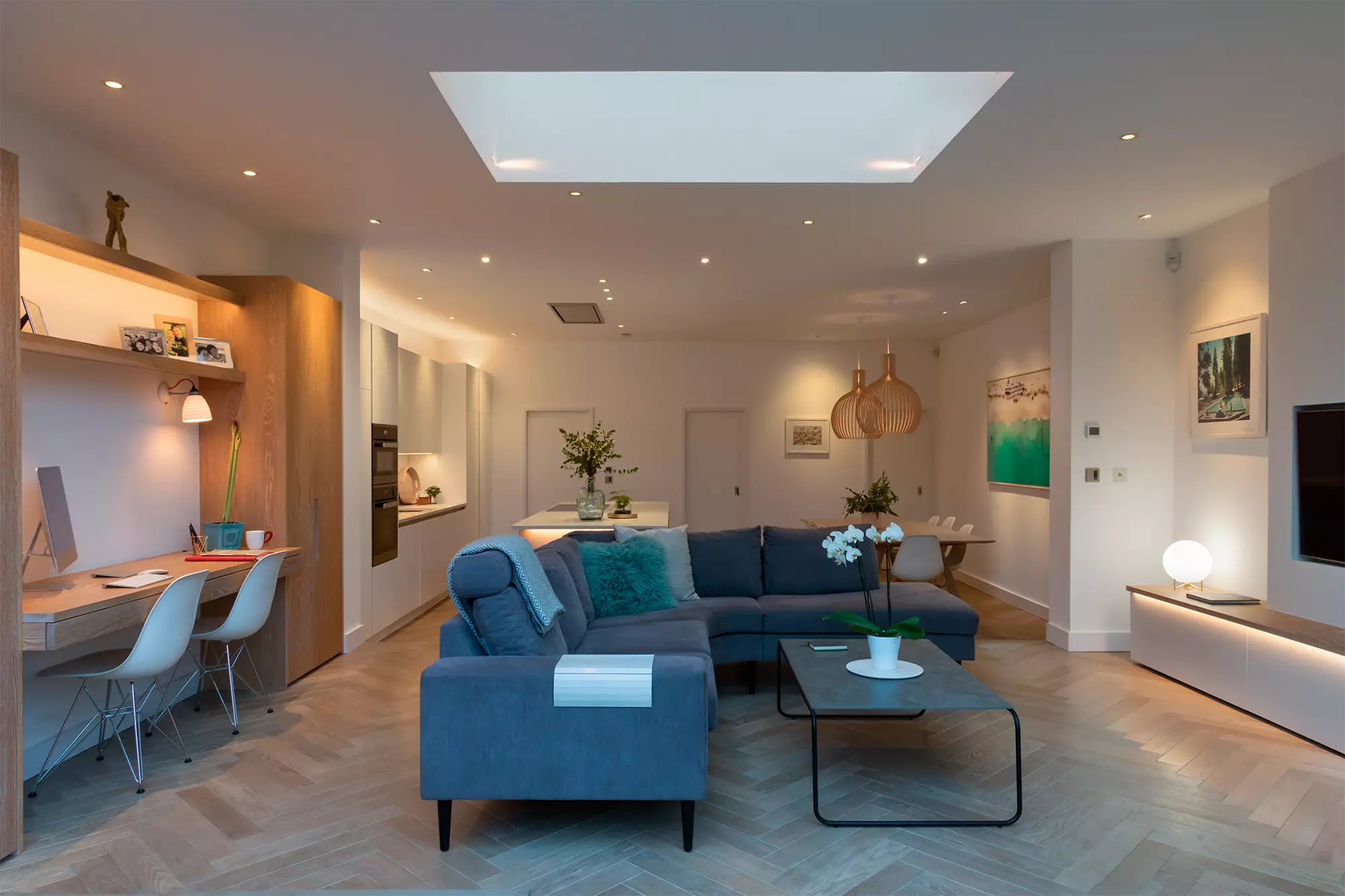 Un soggiorno moderno e ben illuminato dotato di molteplici fonti di illuminazione, tra cui luci da incasso a soffitto e un ampio lucernario