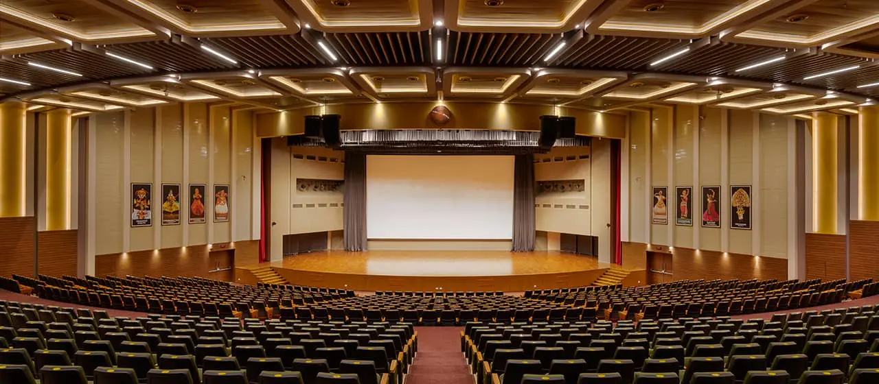 Зал с рядами стульев и сценой, представленный в «Руководстве по освещению зала».