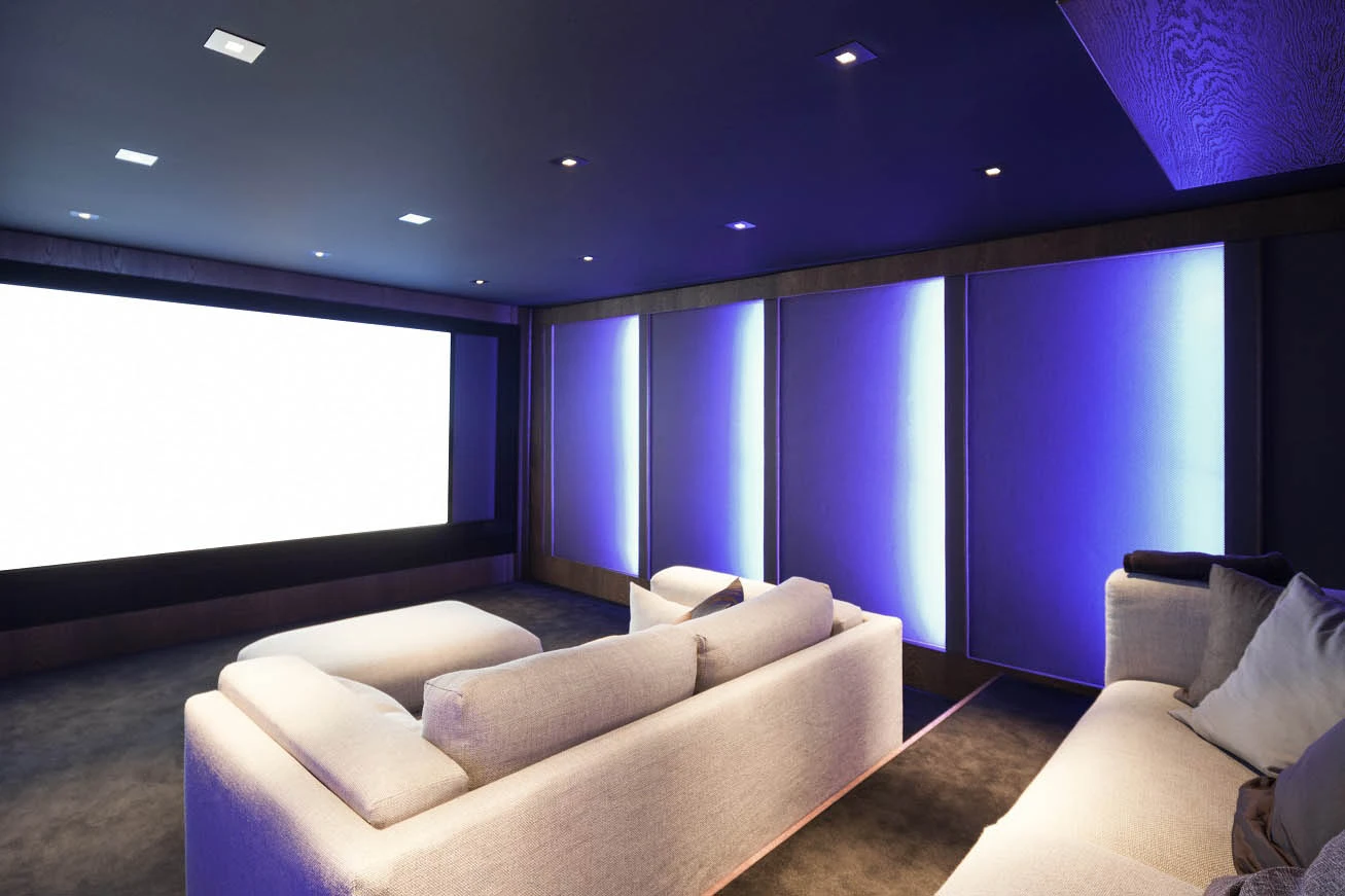 Уютный домашний кинотеатр с диваном и экраном проектора представлен в «Полном руководстве по освещению домашнего кинотеатра».