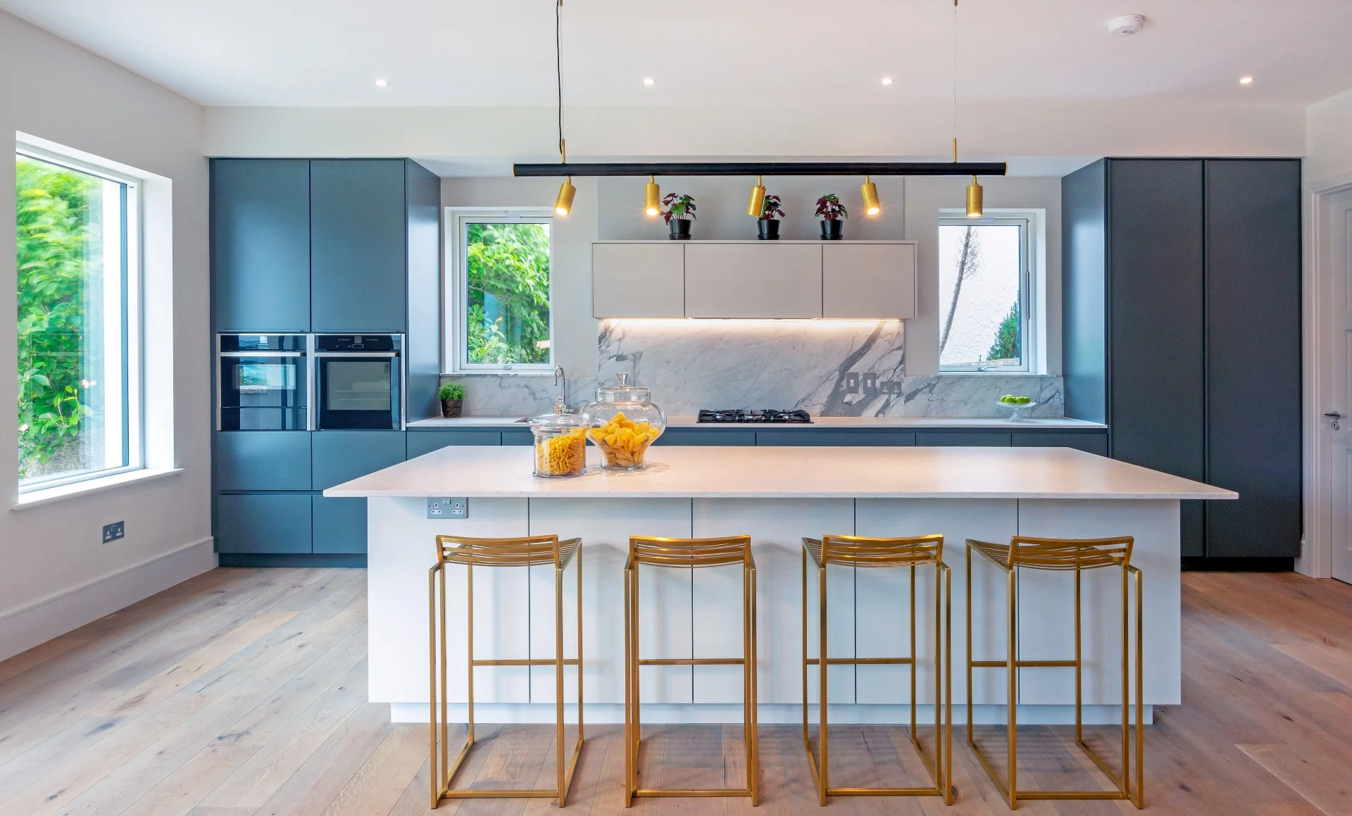 Cozinha moderna apresentando camadas de luz com detalhes suspensos e iluminação natural para criar um espaço funcional e convidativo