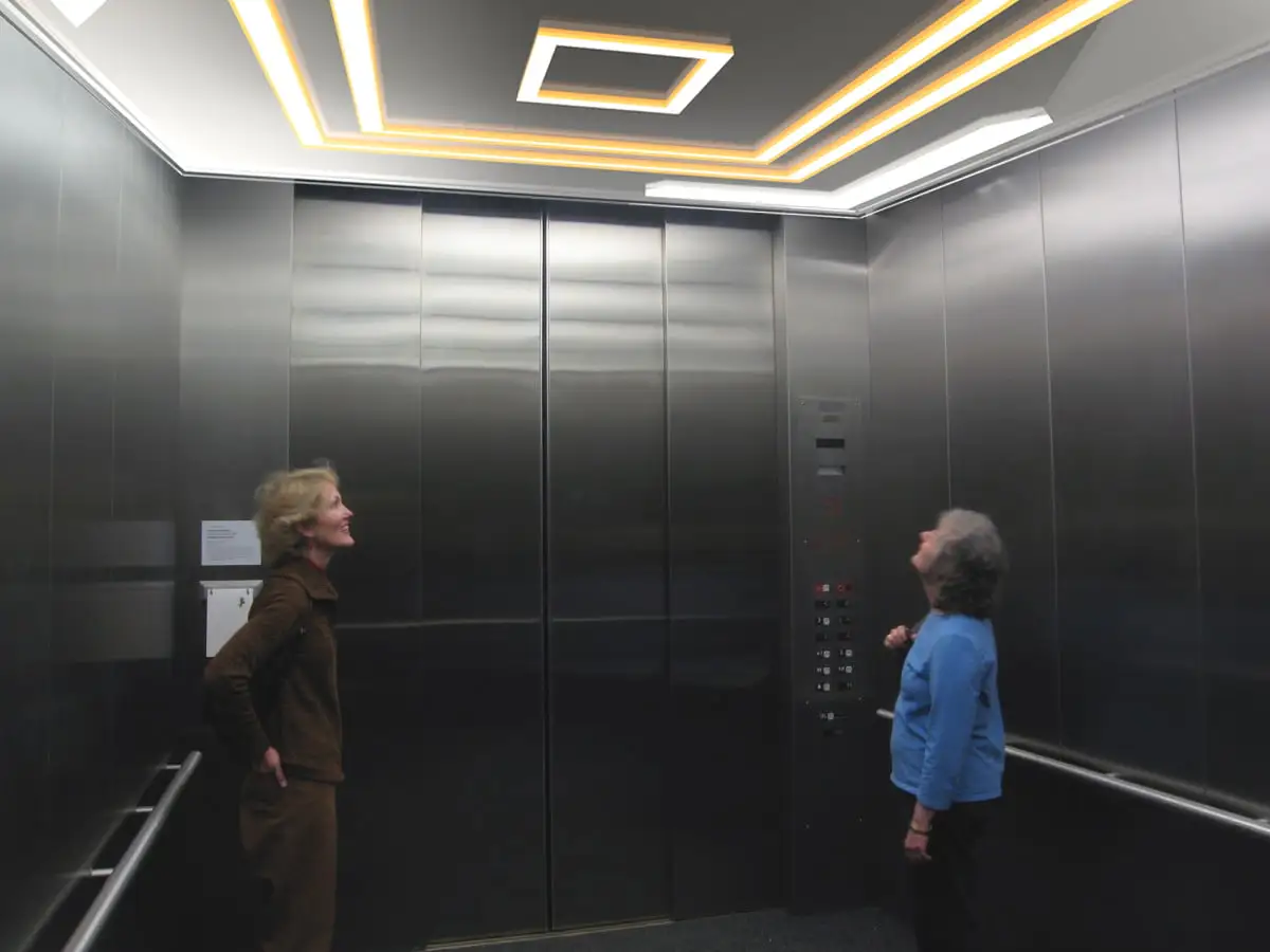 Elevator Cab Lighting Ideas illustrated with two women standing in a well lit elevator